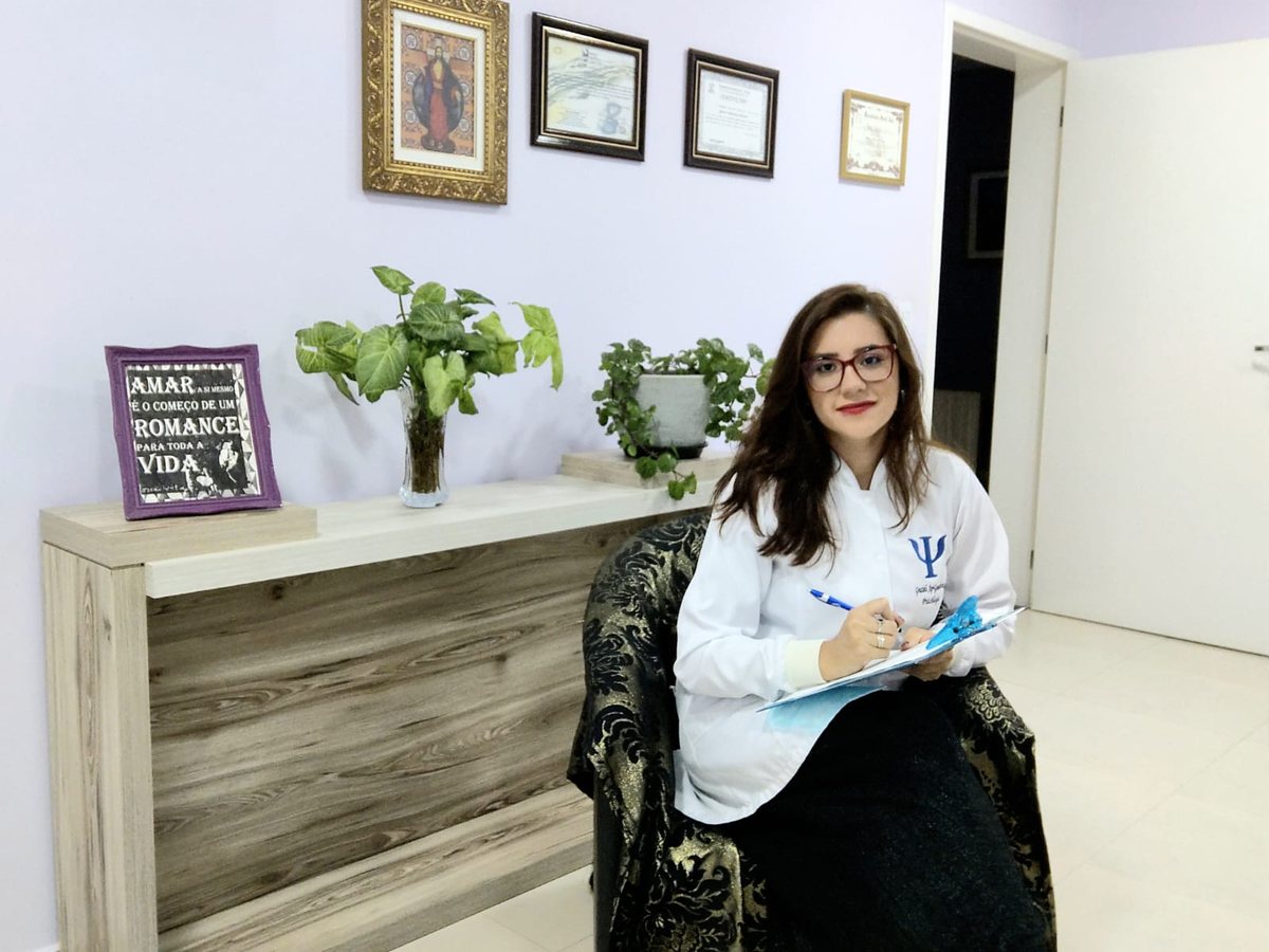 Grazieli em seu consultório, sentada, com prancheta